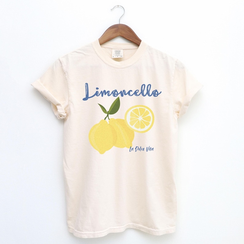 Ivory Beige T-shirt with the text Limoncello, La Dolce Vita, follewed by a juicy lemon graphics.
Limoncello Shirt, La Dolce Vita Tee, Lemon Shirt, Amalfi Coast, Italy TShirt, Vacay T-Shirt, Lemons Tee, Cocktail T Shirt, Retro Graphic Tee