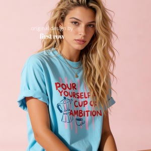 Woman wearing Dolly Parton "Pour Yourself a Cup of Ambition" Shirt, Retro Coffee Graphic, 9 to 5 Country Music Tee, Moka Pot, Coffee Club, Caffeine Lover.

Original desgin and copyright by first row LA.