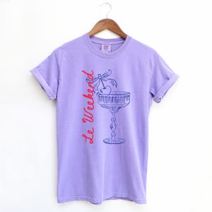 Violet Purple T-shirt with the text Le Weekend and a Cherry Coquette Cocktail graphic.

Because what’s a good time without a little flair?

Perfect for brunch dates, rooftop soirées, or just channeling that effortlessly flirty energy. French twist, retro feel, full-on main character mood.
Weekend Shirt, Le Weekend, French T-Shirt, Weekending, Vintage Aesthetic, Coquette Bow Cherry, Cocktail Tee, y2k T-shirt, weekend vibes tee.