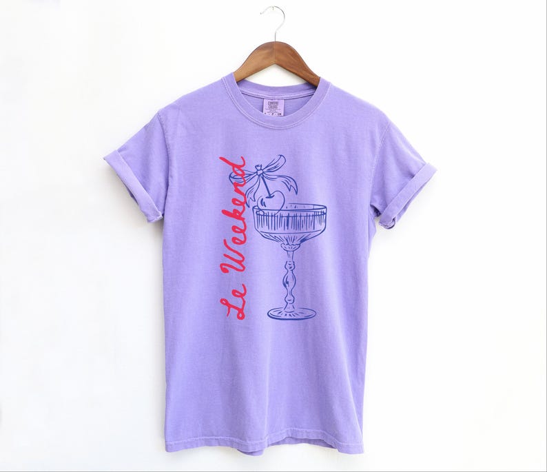Violet Purple T-shirt with the text Le Weekend and a Cherry Coquette Cocktail graphic.

Because what’s a good time without a little flair?

Perfect for brunch dates, rooftop soirées, or just channeling that effortlessly flirty energy. French twist, retro feel, full-on main character mood.
Weekend Shirt, Le Weekend, French T-Shirt, Weekending, Vintage Aesthetic, Coquette Bow Cherry, Cocktail Tee, y2k T-shirt, weekend vibes tee.