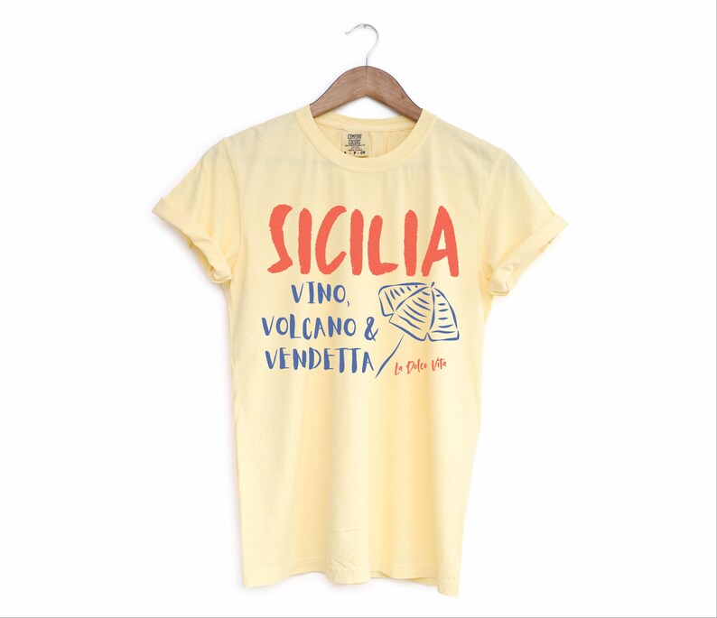 Butter Yellow T-shirt with the text Sicilia, Vino, Volcano and Vendetta, La Dolce Vita. 

A wearable love letter to the drama, beauty, and indulgence of Sicilian culture.

Great for wine lovers, pasta enthusiasts, spontaneous adventurers, and anyone who knows that revenge is a dish best served... with a glass of Nero d’Avola.
Wear it to your next pizza night, wine tasting, or while planning your escape to the Amalfi Coast.