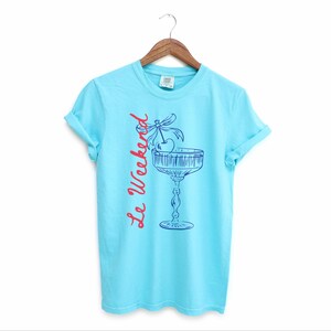 Lagoon Blue T-shirt with the text Le Weekend and a Cherry Coquette Cocktail graphic.

Because what’s a good time without a little flair?

Perfect for brunch dates, rooftop soirées, or just channeling that effortlessly flirty energy. French twist, retro feel, full-on main character mood.
Weekend Shirt, Le Weekend, French T-Shirt, Weekending, Vintage Aesthetic, Coquette Bow Cherry, Cocktail Tee, y2k T-shirt, weekend vibes tee.