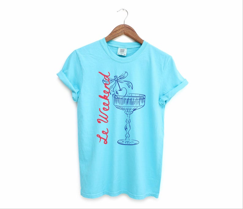 Lagoon Blue T-shirt with the text Le Weekend and a Cherry Coquette Cocktail graphic.

Because what’s a good time without a little flair?

Perfect for brunch dates, rooftop soirées, or just channeling that effortlessly flirty energy. French twist, retro feel, full-on main character mood.
Weekend Shirt, Le Weekend, French T-Shirt, Weekending, Vintage Aesthetic, Coquette Bow Cherry, Cocktail Tee, y2k T-shirt, weekend vibes tee.