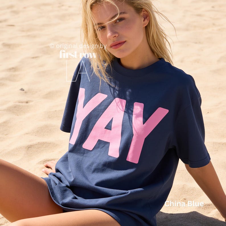 Woman wearing YAY T-Shirt, Happy Pink Graphic Tee, Cute Positive Shirt, Feel Good Tee, Fun Handwritten Statement Shirt, Dopamine shirt.

Original design and copyright by first row LA 2026.