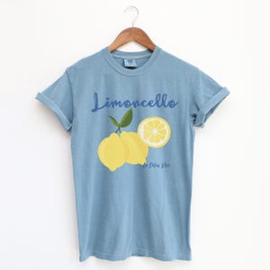 Ice Blue T-shirt with the text Limoncello, La Dolce Vita, follewed by a juicy lemon graphics.
Limoncello Shirt, La Dolce Vita Tee, Lemon Shirt, Amalfi Coast, Italy TShirt, Vacay T-Shirt, Lemons Tee, Cocktail T Shirt, Retro Graphic Tee