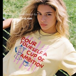Woman wearing Dolly Parton "Pour Yourself a Cup of Ambition" Shirt, Retro Coffee Graphic, 9 to 5 Country Music Tee, Moka Pot, Coffee Club, Caffeine Lover.

Original desgin and copyright by first row LA.