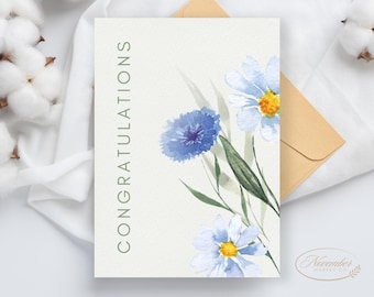 Könnte beinhalten: Eine weiße Karte mit dem Wort "Glückwunsch" in Grün auf der linken Seite gedruckt. Die Karte ist mit Aquarell-Illustrationen von blauen und weißen Blumen verziert.