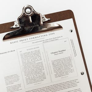 Może przedstawiać: Brązowa podkładka z metalowym klipsem trzymającym białą kartkę papieru. Papier zawiera tytuł "BASIC PRINT FORMATTING TIPS" i tekst o formatowaniu książek. Podkładka znajduje się na białym tle.