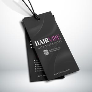 Puede incluir: Dos etiquetas rectangulares negras con el texto "HAIRVIBE HAIR EXTENSIONS" en blanco y rosa. Las etiquetas tienen un c&oacute;digo QR y la direcci&oacute;n del sitio web www.hairvibe.com. Las etiquetas est&aacute;n conectadas por una cuerda negra.