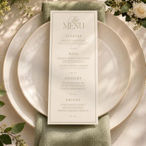 May include: A tall, rectangular cream-coloured menu card with gold text centred on two stacked white ceramic plates. The menu lists sections for Starter, Main, Dessert, and Drinks, featuring items like Frosted Leaf Wedge and Imperial Wagyu Medallion.
