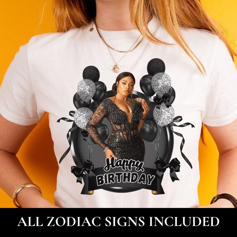 May include: A white t-shirt featuring a graphic print of a person in a black sequined dress surrounded by black and silver glitter balloons. A black banner at the bottom contains the white text Happy Birthday. The design is framed by black ribbons.