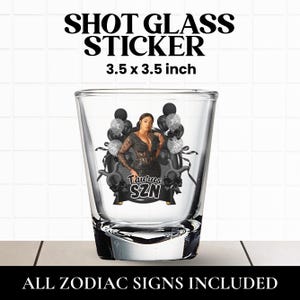 May include: A clear glass shot glass featuring a decorative sticker measuring 3.5 x 3.5 inches. The sticker displays a person in a black dress surrounded by black and silver balloons, with the text Taurus SZN printed in a bold white font.