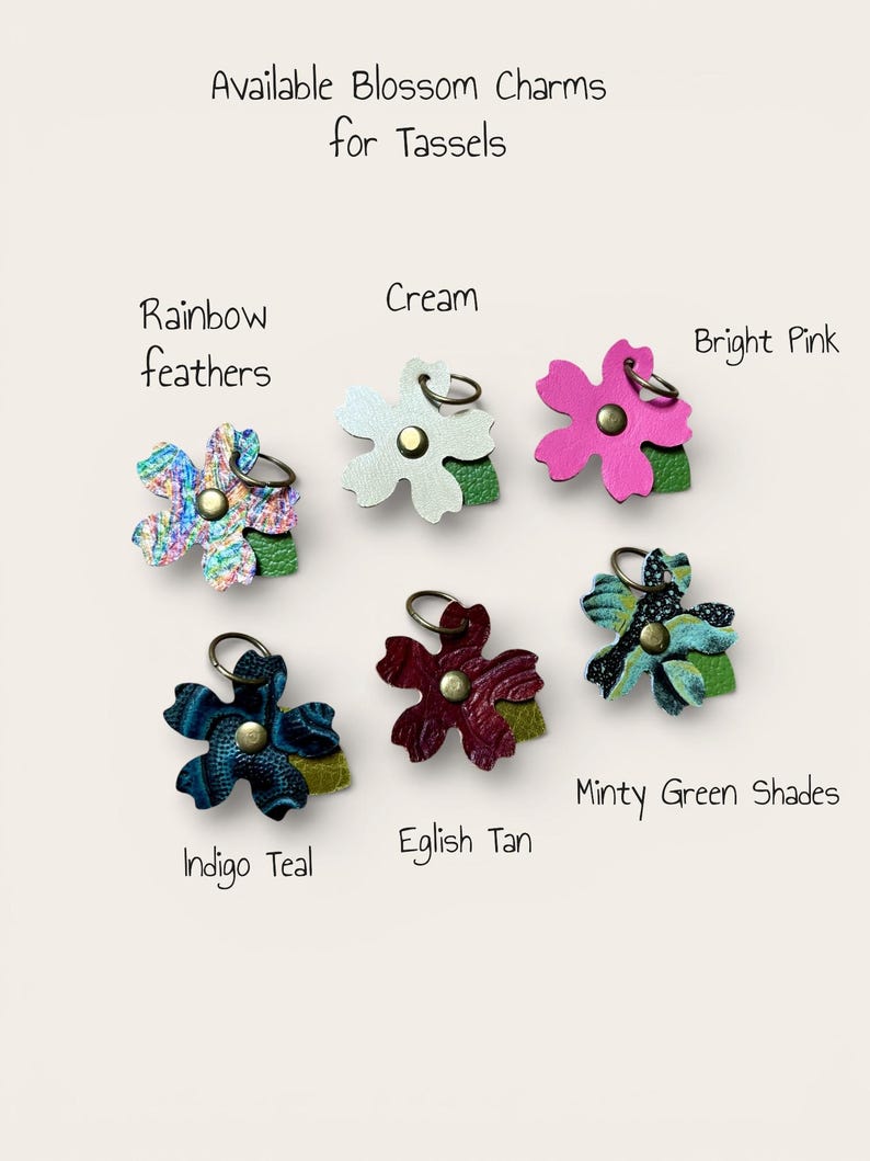 May include: Blossom charms for tassels in a range of colours. The charms include Rainbow Feathers, Cream, Bright Pink, Indigo Teal, Eglish Tan, and Minty Green Shades. Each charm is flower-shaped with a metal ring.