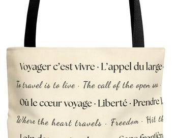 May include: Cream-colored tote bag with black handles featuring French and English text about travel. The text includes phrases like "To travel is to live" and "Where the heart travels."