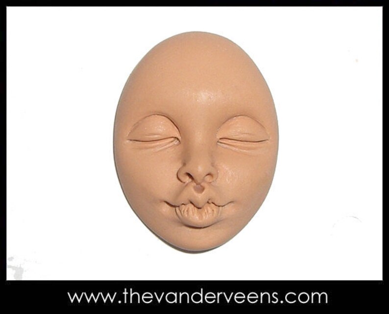 May include: A close-up of a clay sculpture of a face with closed eyes and a smiling mouth. The sculpture is light brown in color and has a smooth texture.