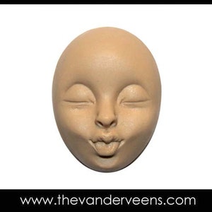 Puede incluir: Una escultura de cer&aacute;mica de un rostro con los ojos cerrados y la boca fruncida, sugiriendo un beso. La escultura es de color beige claro.