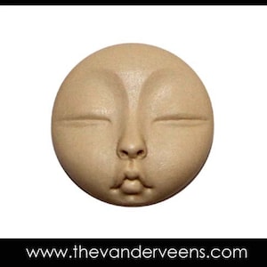 Puede incluir: Una escultura redonda de cer&aacute;mica beige que representa una cara con los ojos cerrados y la boca ligeramente entreabierta. La escultura tiene un acabado liso y mate.