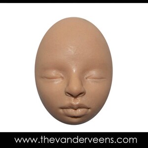 Puede incluir: Un primer plano de una cara esculpida con los ojos cerrados y una expresi&oacute;n neutra. La cara est&aacute; hecha de un material marr&oacute;n claro y tiene forma ovalada.