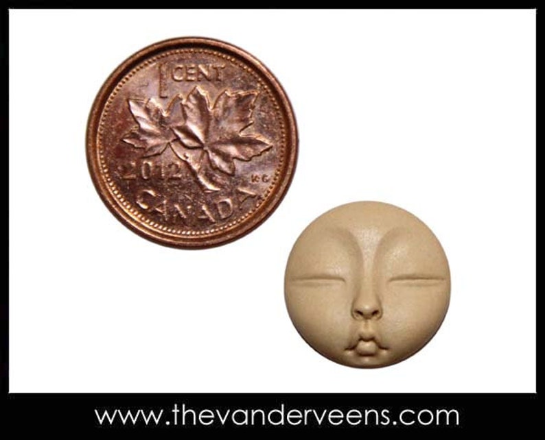 Puede incluir: Primer plano de una peque&ntilde;a cara redonda de color beige con los ojos cerrados y la boca ligeramente entreabierta. La cara es aproximadamente del tama&ntilde;o de una moneda de un centavo canadiense, que tambi&eacute;n se muestra en la imagen.