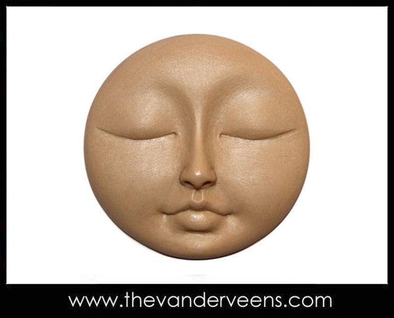 K&ouml;nnte beinhalten: Eine runde, beige Keramik-Skulptur eines Gesichts mit geschlossenen Augen und einem ruhigen Ausdruck.