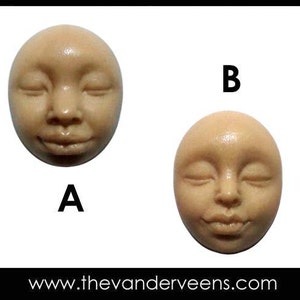 May include: Two round, beige-coloured, ceramic sculptures of faces with closed eyes. The sculptures are labelled A and B.
