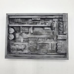 May include: A rectangular wall art piece featuring a complex, three-dimensional arrangement of geometric shapes, mechanical components, and layered bars. The entire structure is finished in a distressed, weathered gray and black metallic paint.