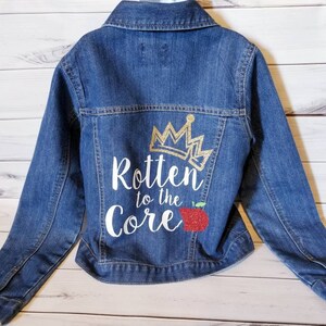 May include: A blue denim jacket with a white design on the back that says "Rotten to the Core" with a gold crown and a red apple.