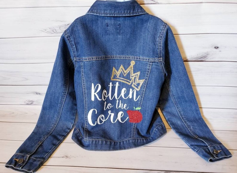 May include: A blue denim jacket with a white design on the back that says "Rotten to the Core" with a gold crown and a red apple.