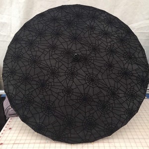 Glittery spiderwebs on a black parasol