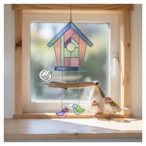 May include: A stained glass birdhouse with a multi-colored roof and geometric design. Below the birdhouse, a wooden perch holds three colorful glass birds. The birdhouse hangs in front of a window.