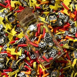 May include: A clear glass jar with a cork stopper filled with colorful polymer clay pieces. The jar is surrounded by yellow lightning bolts, red sticks, orange sticks, and character-shaped pieces with glasses and a lightning bolt scar.