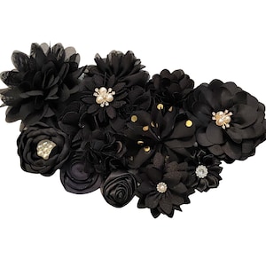 以下が含まれることがあります： ゴールドのドットとパールがあしらわれた黒い布の花のブーケ。花は房状にアレンジされており、あらゆる機会にエレガントなアクセントを加えるのに最適です。