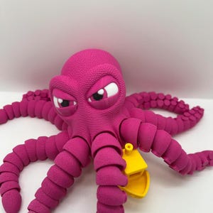 May include: A bright pink octopus toy with a textured surface and articulated tentacles. The octopus has an angry expression with white and black eyes. A small yellow accessory is attached to one of its tentacles.