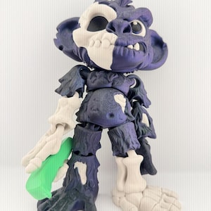 May include: A 3D printed articulated figure featuring a split design with dark purple textured fur and cream-colored skeletal elements. The creature has a skull-like face, exposed bone structures on one arm and leg, and holds a bright green object.