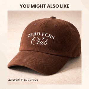 K&ouml;nnte beinhalten: Eine braune Baseballkappe aus Cord mit dem wei&szlig; gestickten Text ZERO FCKS Club und einem kleinen Sternsymbol. Die Kappe verf&uuml;gt &uuml;ber eine strukturierte Krone, einen gebogenen Schirm und gen&auml;hte &Ouml;sen auf den oberen Paneelen im klassischen Design.