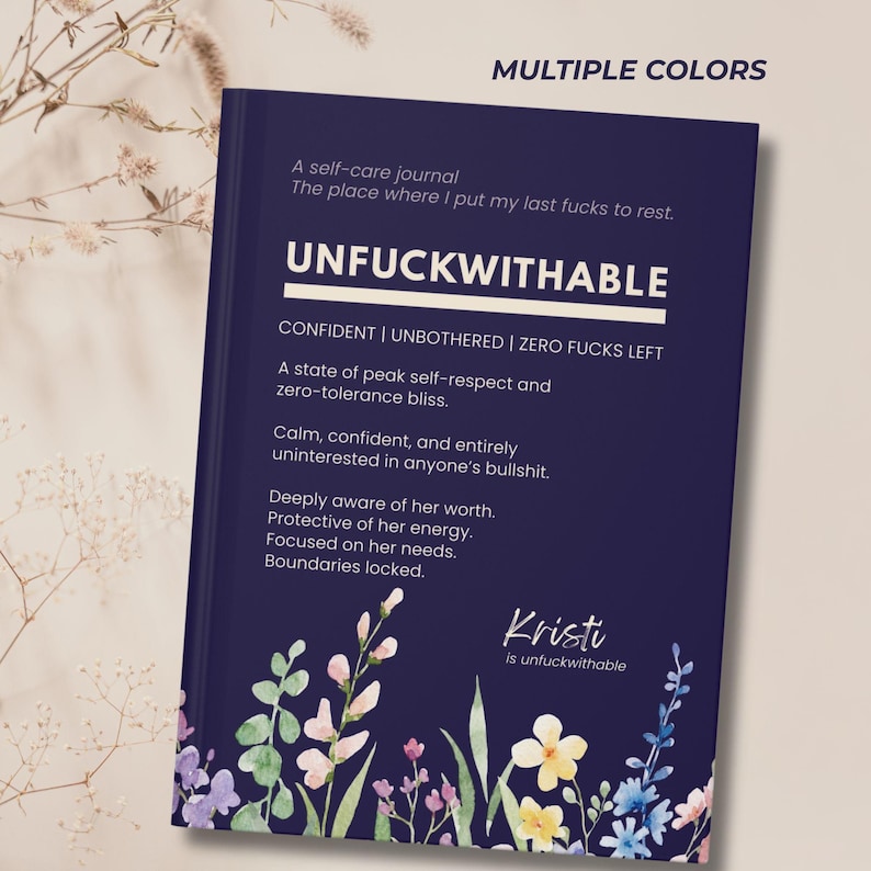 May include: A navy blue self-care journal with the word "UNFUCKWITHABLE" in white. The journal includes text about self-respect and boundaries, with floral illustrations at the bottom. The text "Kristi is unfuckwithable" is also visible.