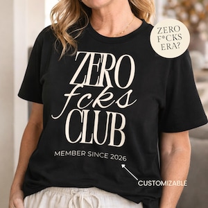 Puede incluir: Una taza de cerámica blanca con un asa negra y el texto "But First, Coffee" en un estilo manuscrito. La taza está sobre una superficie blanca. La taza mide 10 cm de alto.