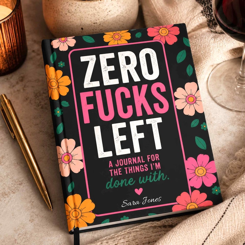 K&ouml;nnte beinhalten: Ein schwarzes Notizbuch mit festem Einband und einem Blumenmuster aus orangefarbenen, rosafarbenen und gelben Bl&uuml;ten sowie gr&uuml;nen Bl&auml;ttern. Der Text auf dem Einband lautet: ZERO FUCKS LEFT, A JOURNAL FOR THE THINGS I'M done with., und Sara Jones, mit einem kleinen rosa Herz.