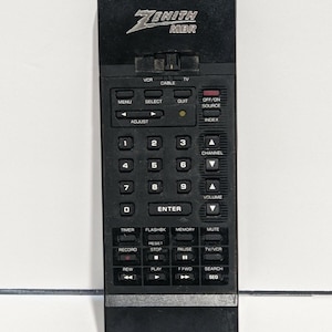 May include: Black Zenith MBR remote control with multiple buttons for TV, VCR, and cable functions. Features buttons for channel, volume, and menu options. The remote has the Zenith logo at the top.