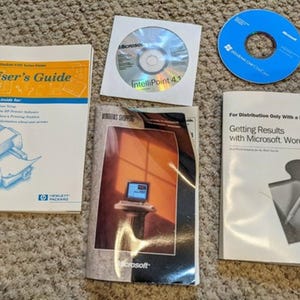 May include: A collection of computer software materials including an HP DeskJet 670C Series User's Guide, a Microsoft IntelliPoint 4.1 CD in a paper sleeve, a blue Windows Live OneCare CD, a Windows software booklet, and a Microsoft Word 97 manual.