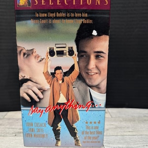 Op de afbeelding: Een VHS-band van de film "Say Anything..." met John Cusack. De cover toont een man die een boombox boven zijn hoofd houdt, met de titel van de film in een gestileerd lettertype. De band is gelabeld "Selections".