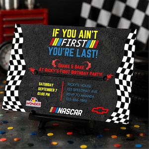 May include: A rectangular racing-themed birthday invitation card with a black asphalt texture background, featuring checkered side borders, the text IF YOU AIN'T FIRST YOU'RE LAST, SHAKE & BAKE AT RICKY'S FIRST BIRTHDAY PARTY, and NASCAR branding.