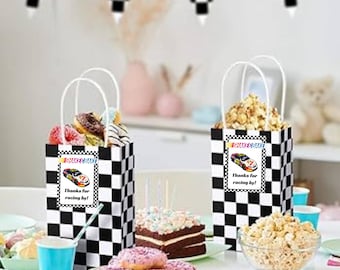 Puede incluir: Dos bolsas de regalo a cuadros blancos y negros llenas de donuts y palomitas de maíz, con temática de carreras. Cada bolsa tiene una etiqueta que dice "Shake & Bake" y "Thanks for racing by!". Una mesa está puesta con golosinas y decoraciones.