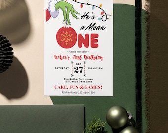 May include: A Grinch-themed first birthday party invitation with a red and white ornament, green hand, and the text "He's a Mean One". The invitation includes the date, time, and location of the party.