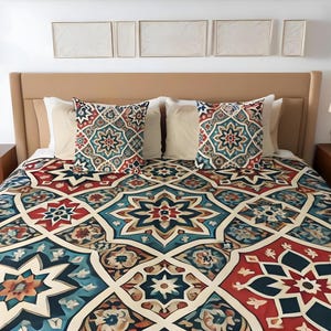 Könnte beinhalten: Ein Bett mit einer gemusterten Bettdecke und zwei gemusterten Kissen. Die Bettdecke und die Kissen haben ein geometrisches Muster in Blautönen, Rot und Gold. Das Bett hat ein cremefarbenes Kopfteil und einen weißen Bettrahmen.