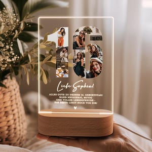 May include: A personalized LED night light with a wooden base. The light features the number "16" filled with photos, the name "Luise Sophia", and German text. The light is held in a person's hand.