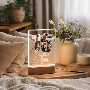May include: A lighted acrylic photo display in the shape of the number 16, with multiple photos inside. The base is a brown wooden rectangle. Text includes a name and a birthday message. The display is on a wooden tray.