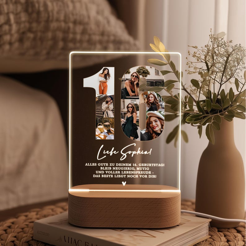 May include: A personalized LED night light with a wooden base. The light features a collage of photos forming the number 16, with text that reads "Liebe Sophia!" and a birthday message. The light is on a stack of books.