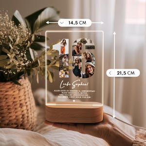 May include: A personalized LED night light, 8.5 inches tall and 5.7 inches wide, with a wooden base. The light features a collage of photos forming the number 16, with text below. The light is held by a person's hand.