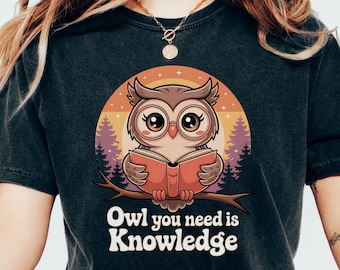 May include: A black t-shirt with a cartoon owl reading a book. The owl is brown and has big eyes. The text on the shirt says "Owl you need is Knowledge".